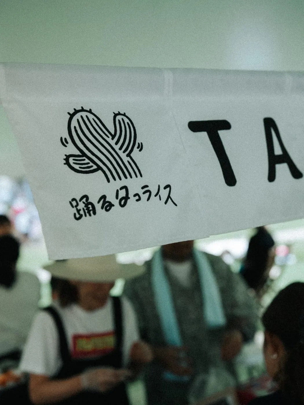 「踊るタコライス」の出店ブース。テントに店名の書かれた幕が掲げられ、スタッフが調理をしている。